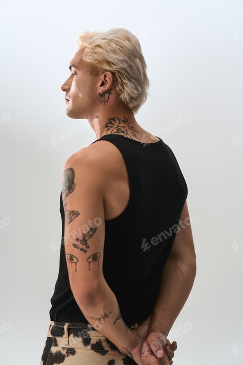 Preview: Stylish young man with tattoos exudes confidence in modern fashion setting