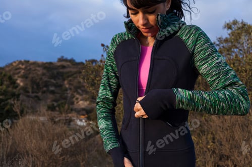 Preview: Woman zipping up her jacket on a cool outdoor hike