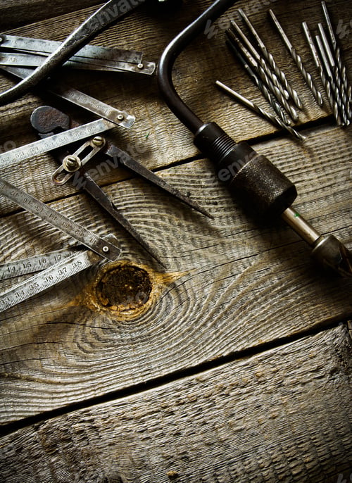 Preview: Old drill, compasses, ruler and drills on a wooden background.