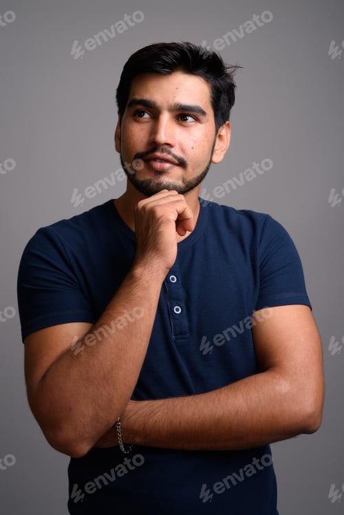 Preview: Young handsome bearded Persian man against gray background
