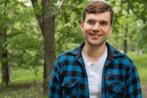 Preview: cheerful young man looking at camera in green park