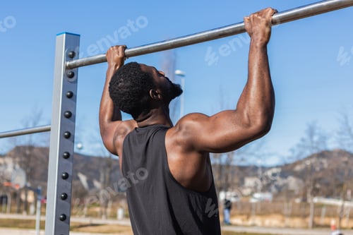 Preview: Unrecognizable strong black sportsman working out on bar in town