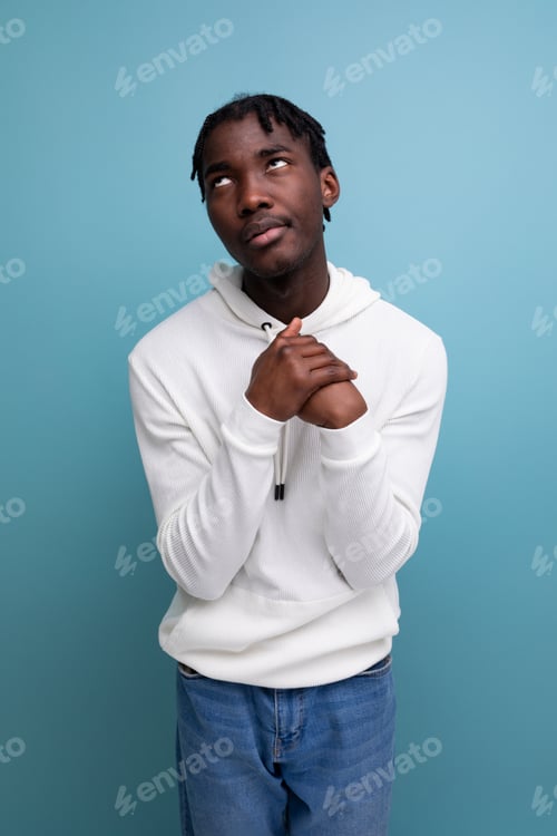 Preview: thinking model dark-skinned young brunette man looks away in a white sweater