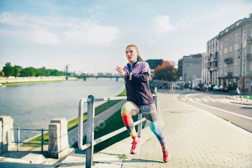 Preview: Mid adult female runner running along riverside