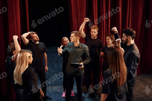 Preview: Practice in progress. Group of actors in dark colored clothes on rehearsal in the theater