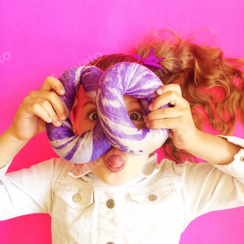 Preview: Playful Child Holding Donut On a Pink Background