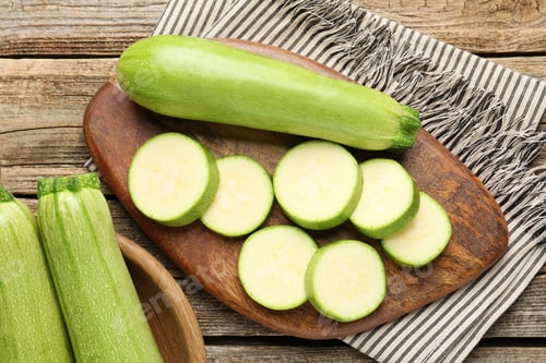 Preview: Fresh ripe zucchinis on wooden table, flat lay. Whole and cut
