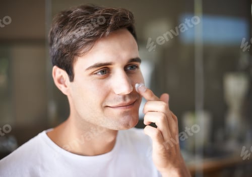 Preview: Closeup of a young man applying lotion to his face
