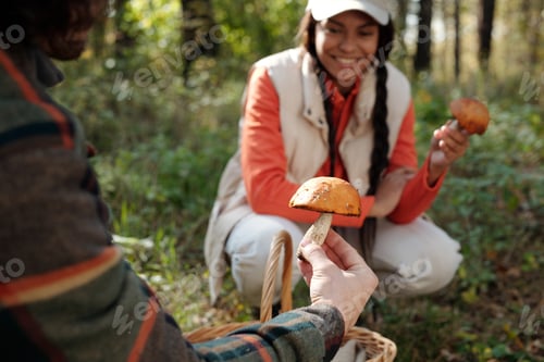 Preview: Focus on hand of young man holding boletus in front of camera