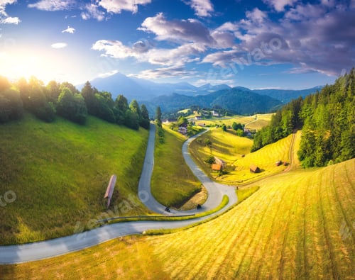 Preview: Aerial view of country road in green meadows at sunset in summer
