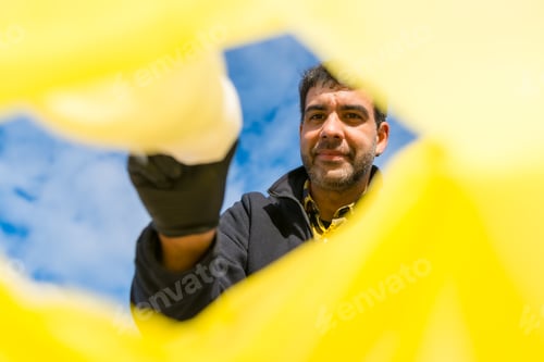 Preview: Man throwing a plastic bottle into a garbage bag on the beach. Ecology, Sea pollution
