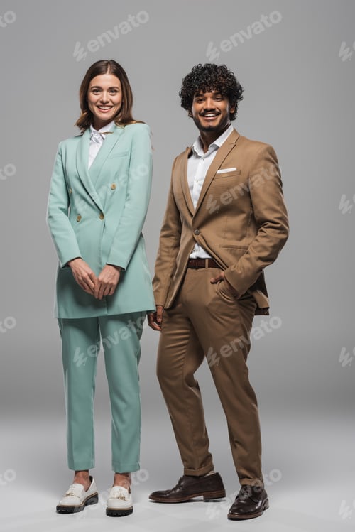 Preview: Full length of smiling interracial event hosts in formal wear looking at camera and posing