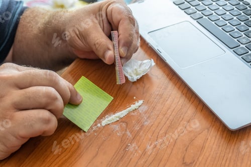Preview: Closeup of a male hand preparing a cocaine line on the desk of the office