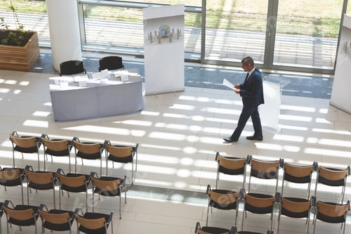 Preview: High angle view of businessman practising speech in empty conference room in office