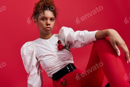 Preview: Young woman showcases stylish red outfit with elegance against a vibrant backdrop
