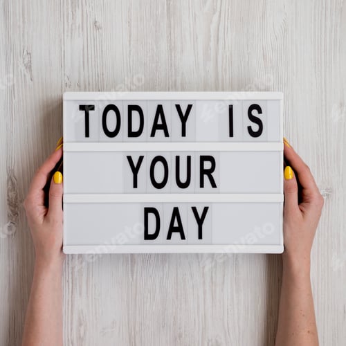 Preview: Female hands hold modern board 'Today is your day' words over white wooden background, top view.