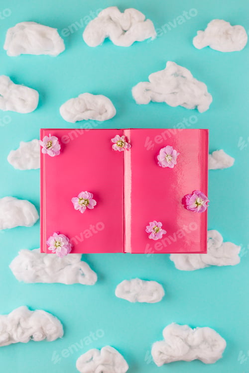 Preview: Writer desk concept. Pink open book with clouds. Top view.