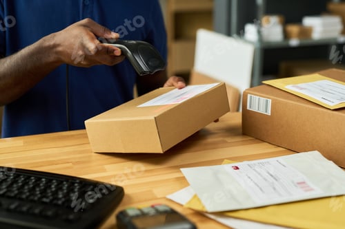 Preview: Young Adult Black Man Scanning Parcel with Barcode Reader at Shipping Desk