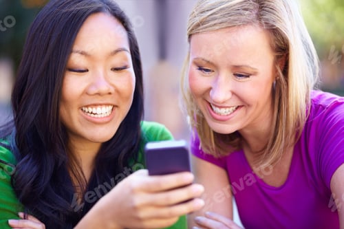 Preview: Look, he texted me back. Two young woman reading an sms together.