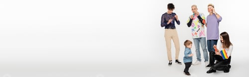 Preview: toddler boy near young lgbtq community friends blowing soap bubbles on grey background, banner