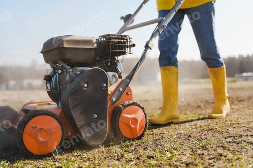 Preview: Woman villager is using aerator machine to scarification and aeration of lawn or meadow