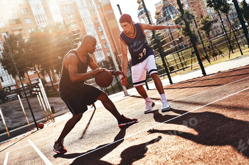 Preview: Showing his skills. Two young men in sports clothing playing basketball while spending time outdoors