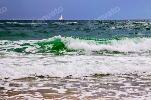 Preview: Ocean waves and coast.Sailboat on the background.Water foam in the sand.