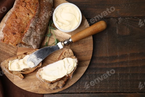 Preview: Tasty bread with butter and knife on wooden table, top view. Space for text