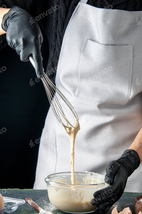Preview: front view female cook in mask mixing up ingredients and making dough on a dark background cuisine