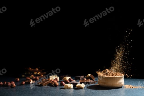 Preview: Cocoa powder in motion. Chocolate dust, cacao products, nuts on black background. Copy space