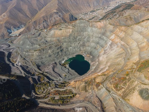 Preview: Aerial view of a large open-pit mine with a lake near a village