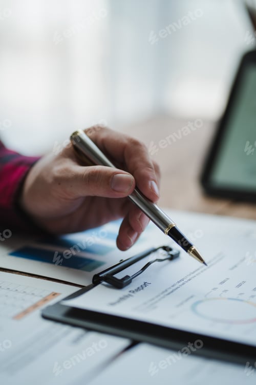 Preview: Businessman analyzing financial report with charts and graphs using pen