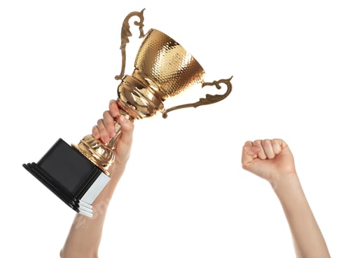 Preview: Young woman holding gold trophy cup on white background, closeup