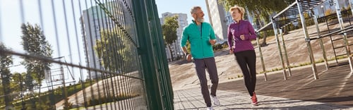 Preview: Morning jog. Active mature family couple in sportswear running together at the stadium in the