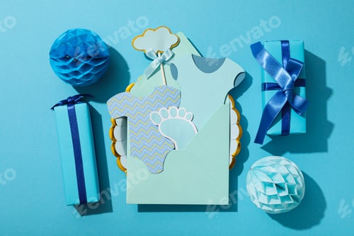 Preview: Paper baby things in envelope and gift boxes on blue background, top view