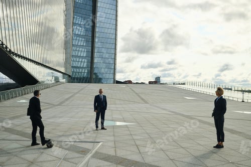 Preview: Group of Businesspeople Standing Outdoors to Play with Soccer Ball