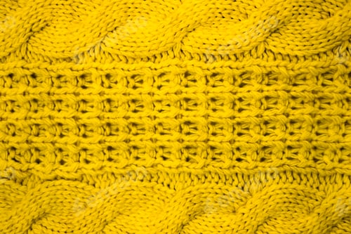 Preview: The texture of a knitted woolen thread in yellow color close-up.
