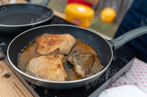 Preview: Cooking fish fillets in frying pans outdoors during a sunny summer afternoon gathering
