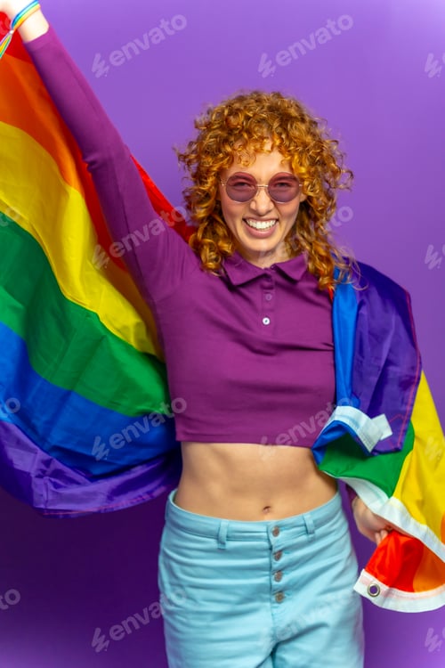 Preview: Woman with curly hair and sunglasses waving lgbt rainbow flag