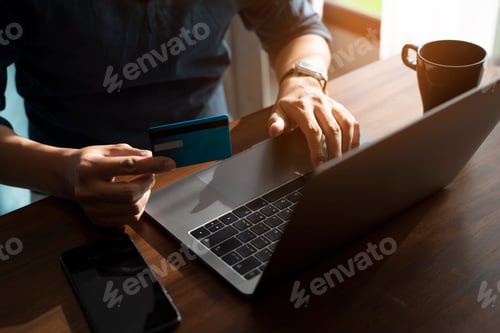 Preview: Male hand holding credit card and using laptop.