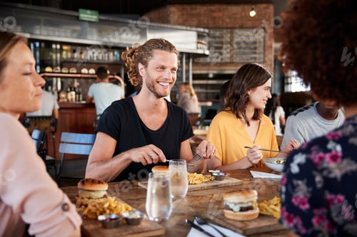 Preview: Group Of Young Friends Meeting For Drinks And Food In Restaurant