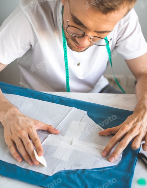 Preview: A self-taught designer in white t-shirt and glasses works with fabric, pattern and chalk. A male DIY