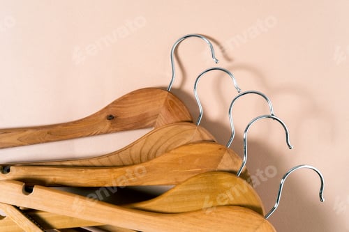 Preview: Top view of wooden hangers lying on a beige background.