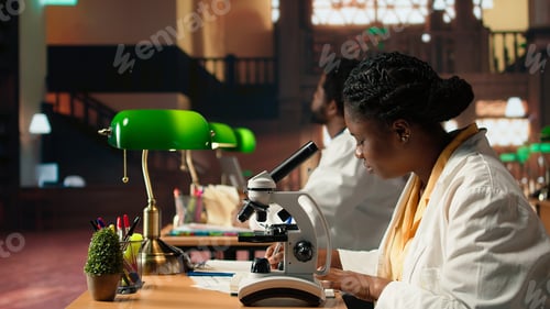 Preview: Female student working with a microscope to prepare for microbiology lessons