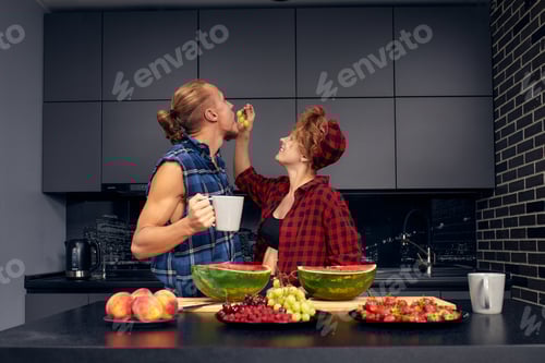 Preview: Happy couple standing in kitchen at home preparing together yummy dinner on first dating, spouses