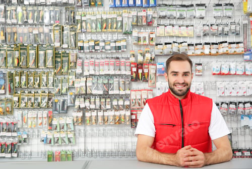 Preview: Salesman standing near showcase with fishing equipment in sports shop. Space for text