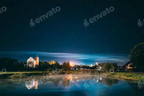 Preview: Night Clouds Over River Lake Near Houses In Village. Night Starry Sky Above Lake River With Bright