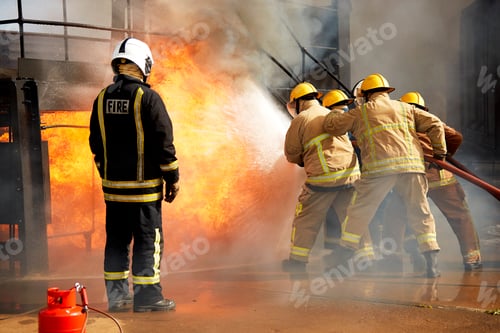 Preview: Firemen training, firemen spraying water at fire at training facility, rear view