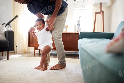 Preview: Father Encouraging Baby Daughter To Take First Steps At Home