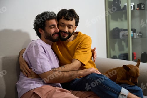 Preview: Happy lgbt couple embracing on sofa with dog at home